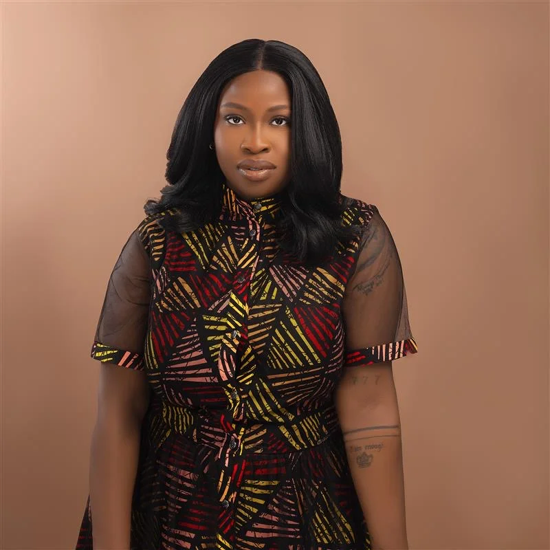 TeeJay B, founder of 7 Star Standard, in a red, gold, and black patterned dress